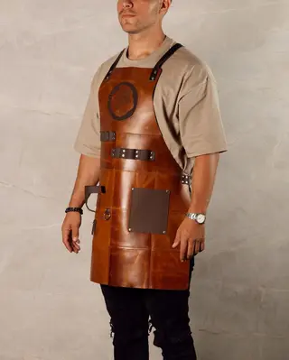 Patterned tan leather BBQ apron worn, showing the stitched panels and the pocket