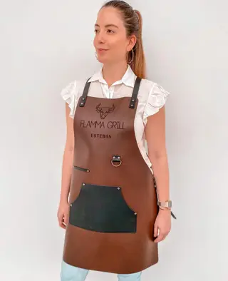 Woman wearing a tan apron with a black pocket and an engraved logo