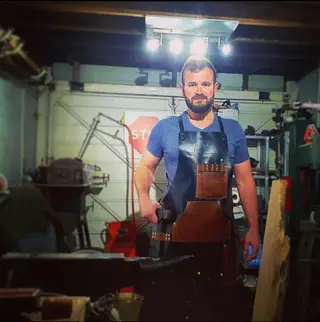 Smith wearing a black split-leg apron in his forge