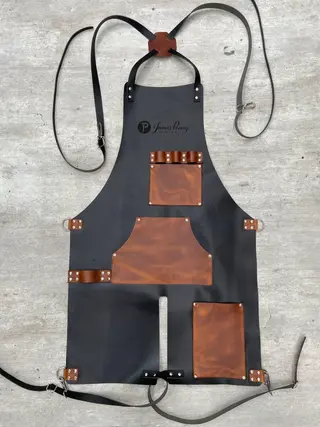 Black split-leg apron with tan pockets, laid flat