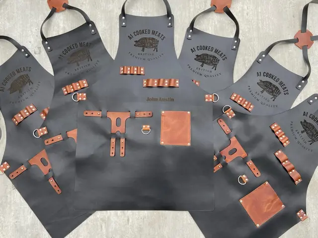 Several black leather aprons laid out together, each engraved with a business logo