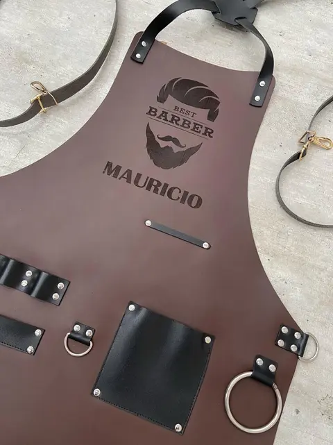 Dark brown barber apron engraved with a name and logo