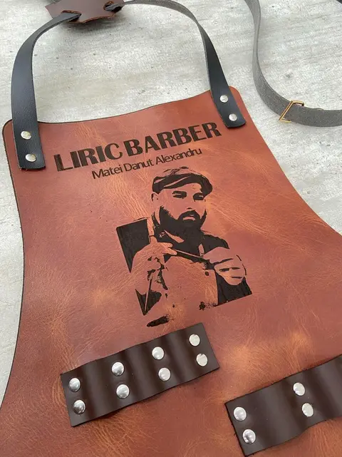 Tan leather apron engraved with a barbershop's portrait logo
